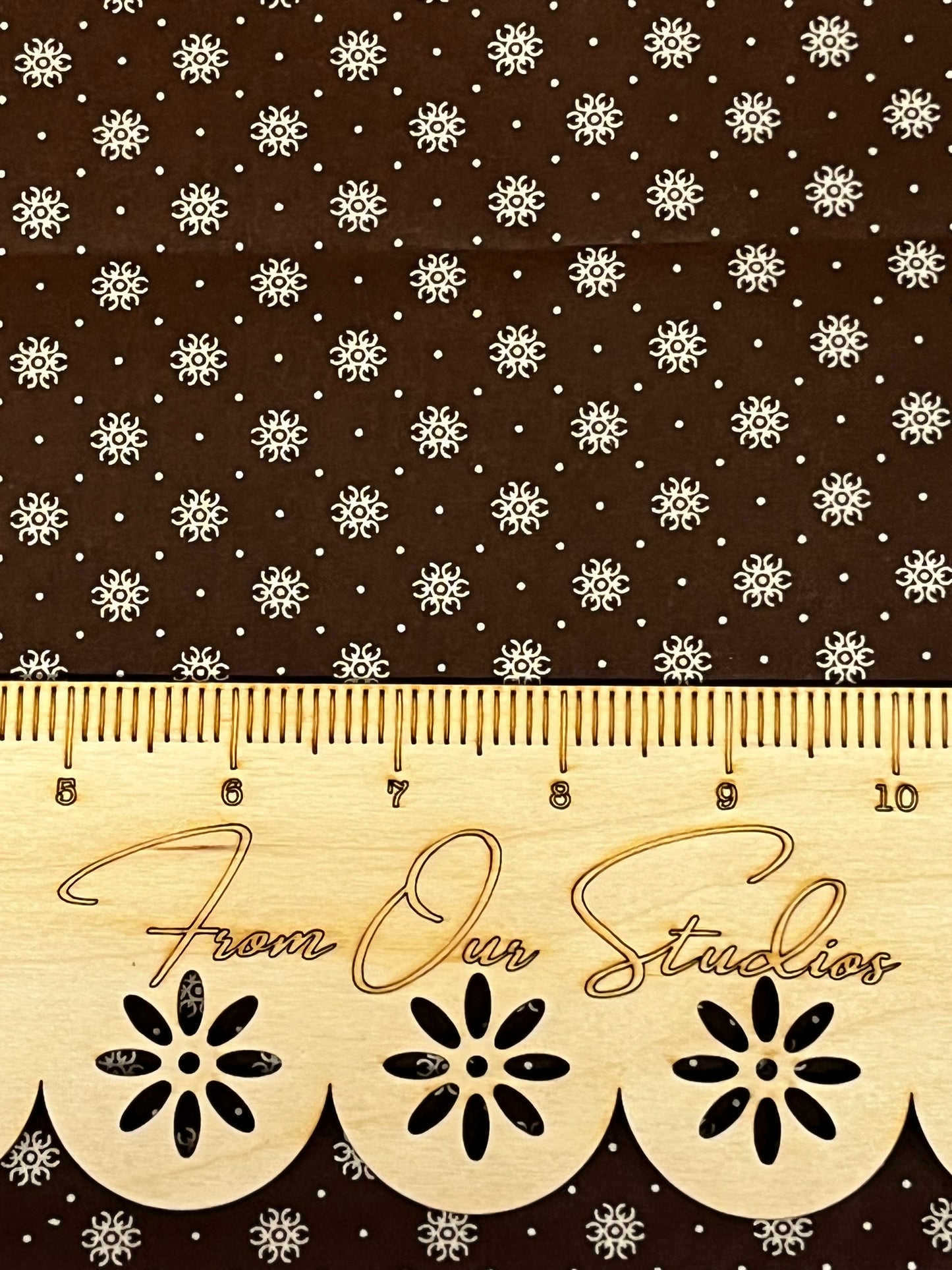 Close-up of brown reproduction cotton fabric with small cream star motifs, quilting weight fabric in fat quarter size.