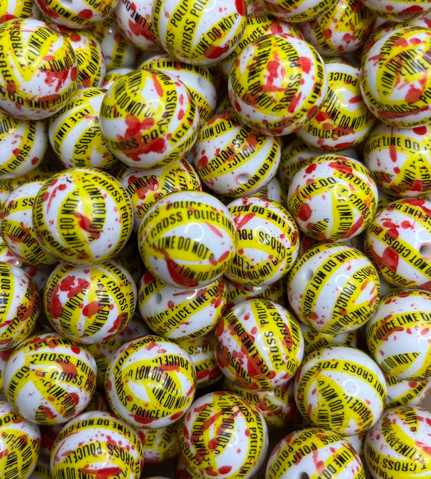 Close-up of 20MM Police Line bubblegum beads with yellow tape and red blood splatter design, #B1006 from Revitalized Studios