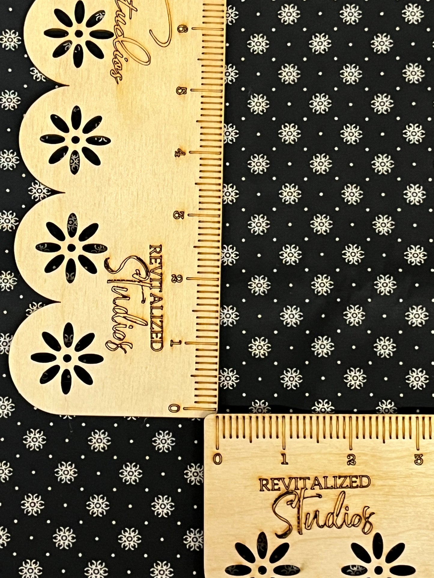 Black reproduction fabric with cream floral starburst print by Marshall Dry Goods, shown with ruler for scale.