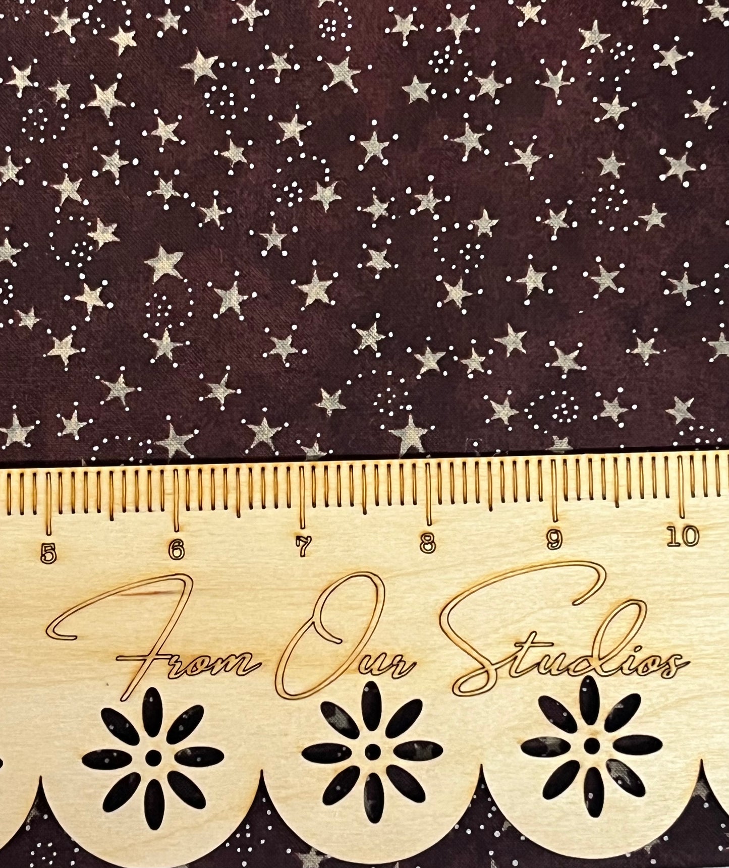 Close up of burgundy riley blake fat quarter fabric with constellations and a ruler for scale