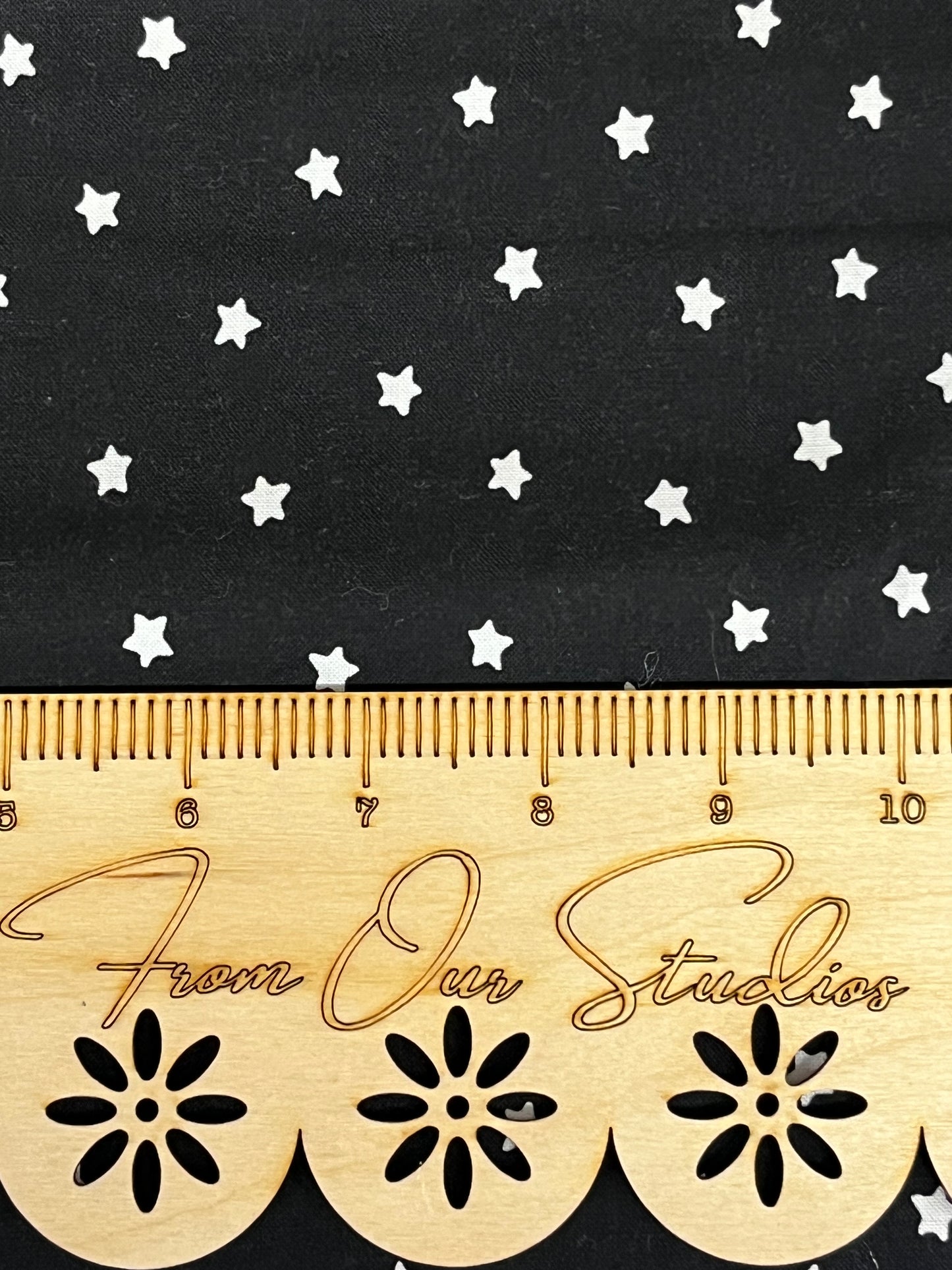 Close view of white star print on black Riley Blake cotton fabric, quilting and craft fabric