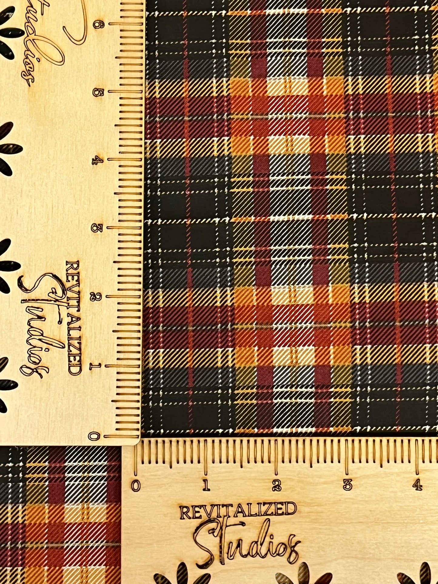 A fat quarter of fabric from the John Wayne Courage Collection with a fall and Halloween plaid pattern. The fabric is primarily black, orange, red, yellow, and white, and the image includes a ruler for scale.