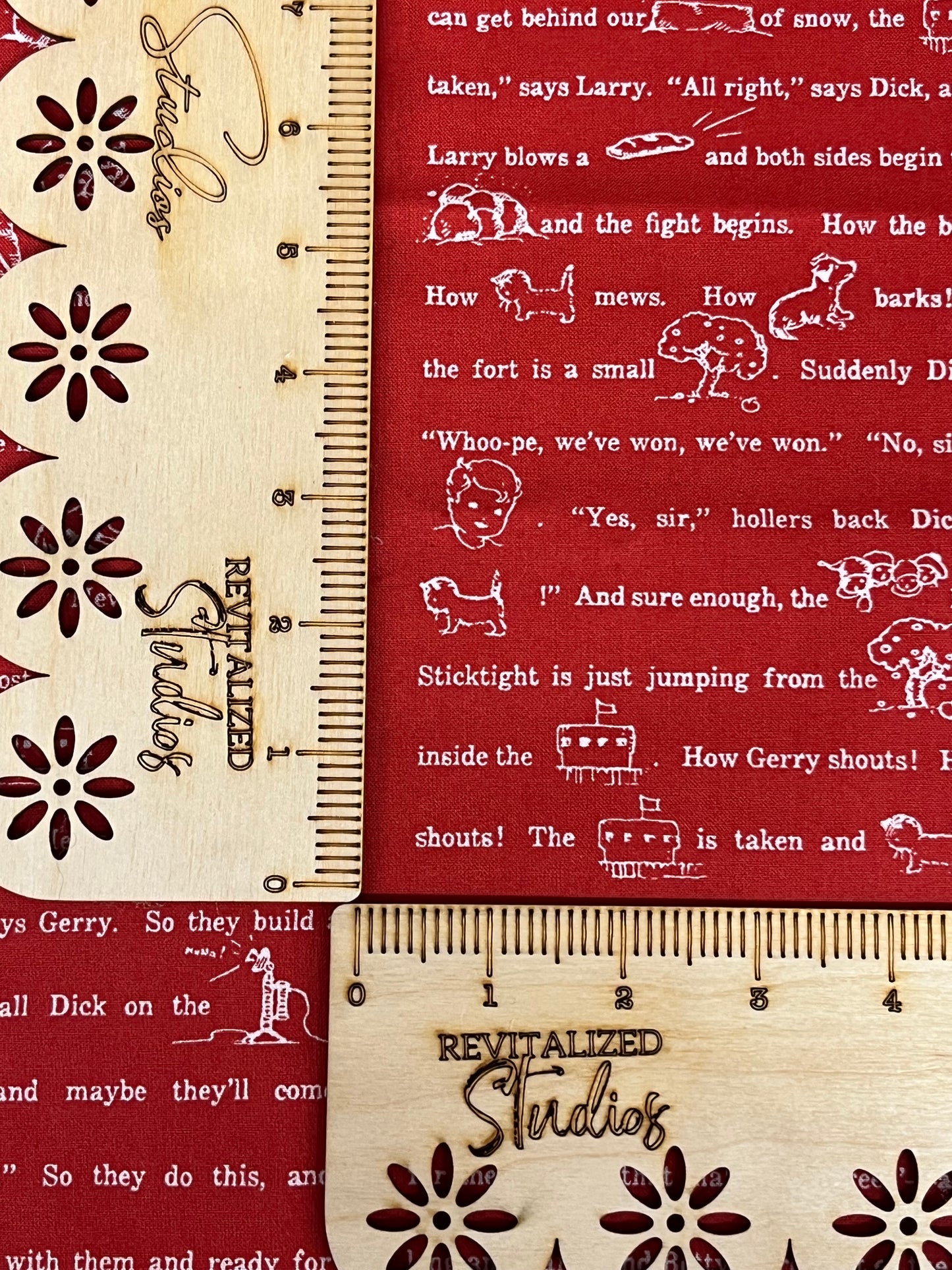 A fabric from Riley Blake Designs featuring a red background with white snowflake patterns and fun sayings in a wooden ruler style font.