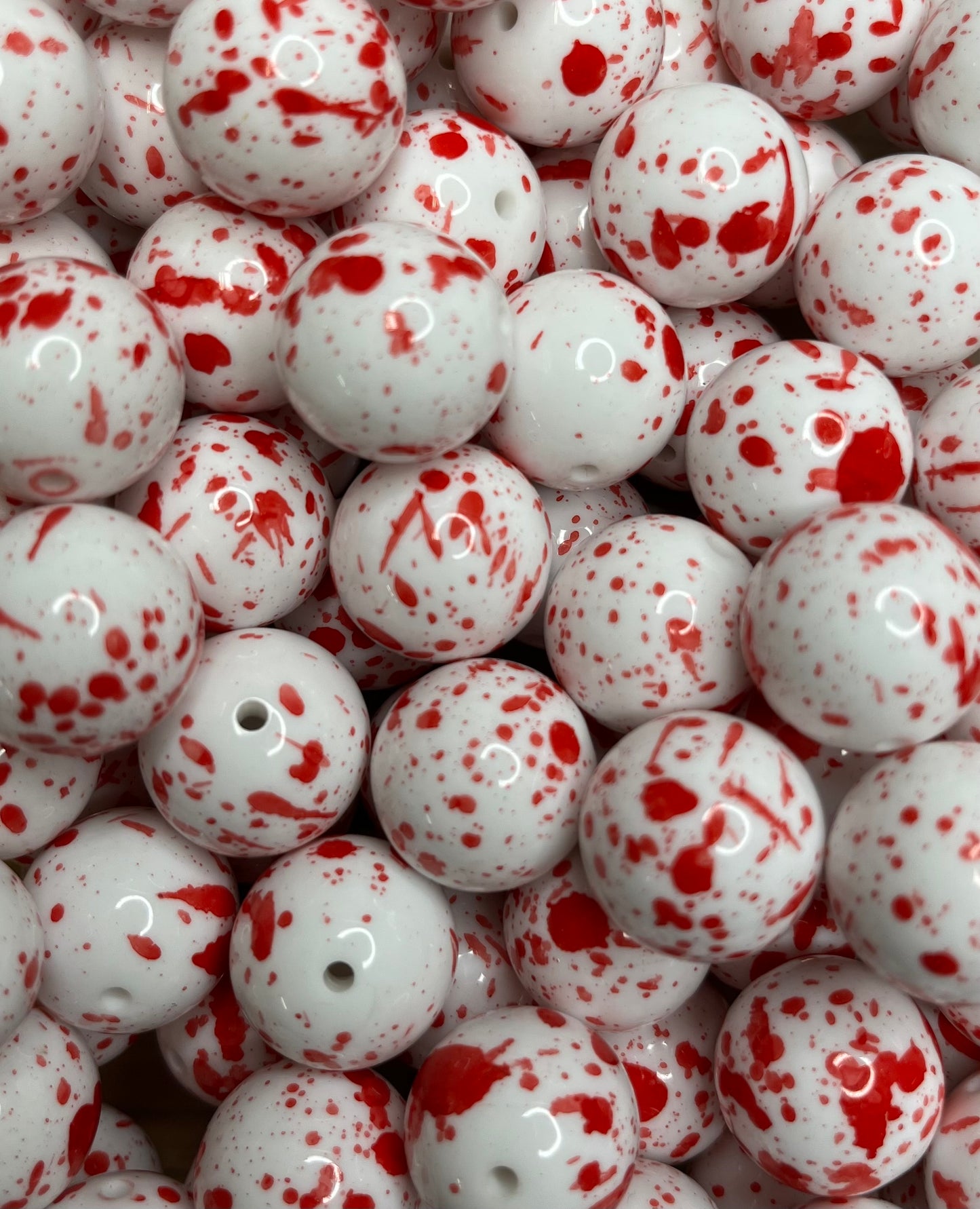 Close-up of glossy white 20mm acrylic bubblegum beads with red blood spatter paint design