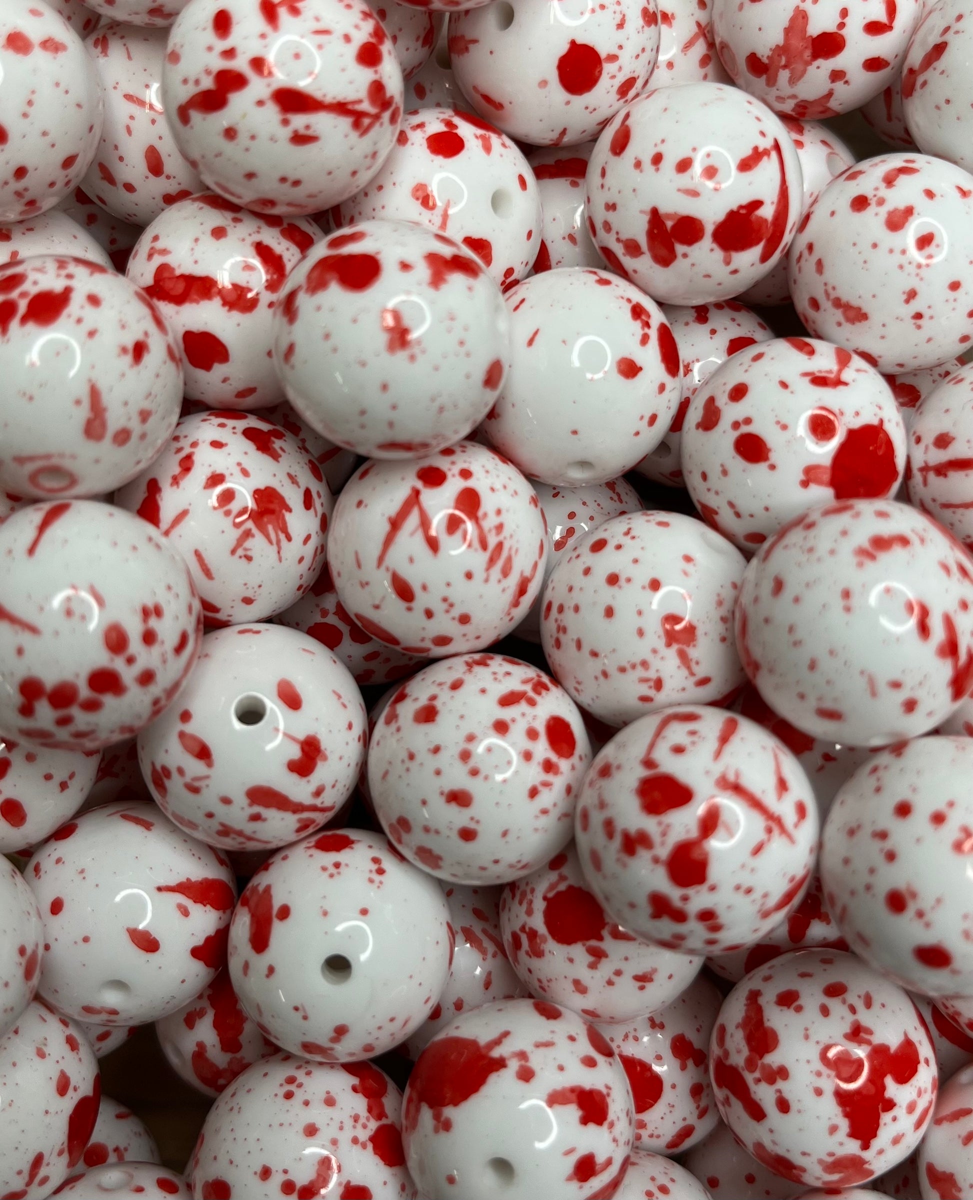 Close-up of glossy white 20mm acrylic bubblegum beads with red blood spatter paint design
