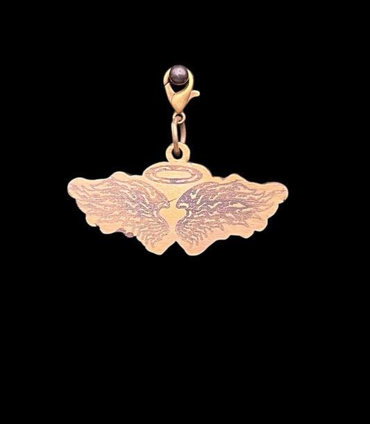 Hand stamped birch angel wings charm with halo design, measuring 0.5 by 1.5 inches, shown against a black background. Ideal for junk journaling, mixed media, or whimsical craft projects.