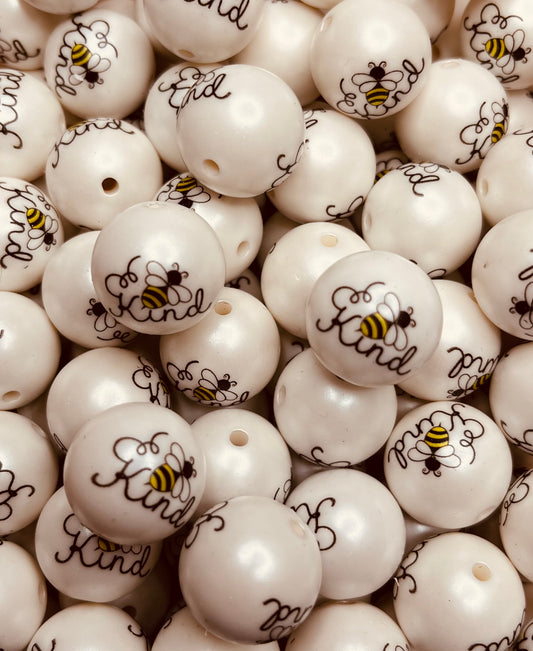 Close-up of white “Bee Kind” 20mm bubblegum beads featuring black script and yellow bumblebee design