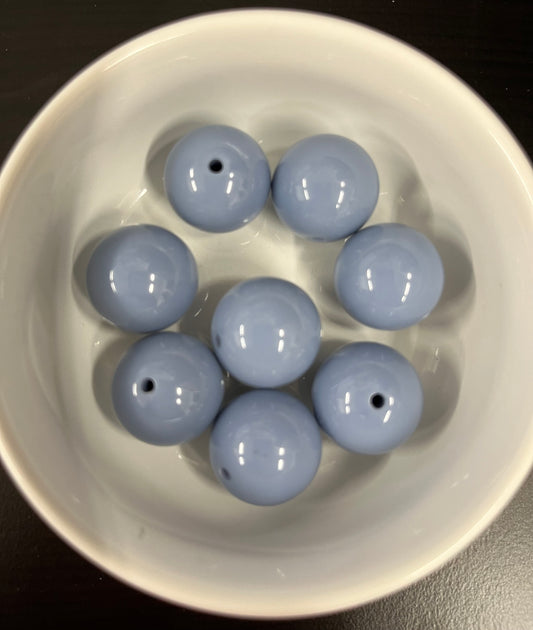 White bowl with eight gray blue beads on a dark background