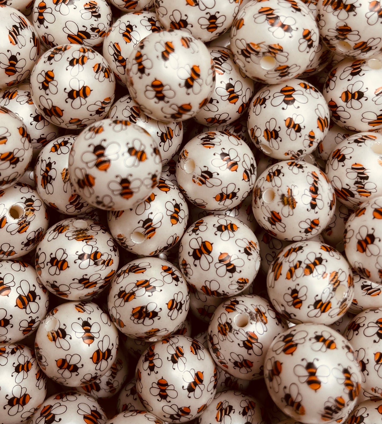 Close-up of white 20mm acrylic bubblegum beads printed with yellow and black bees