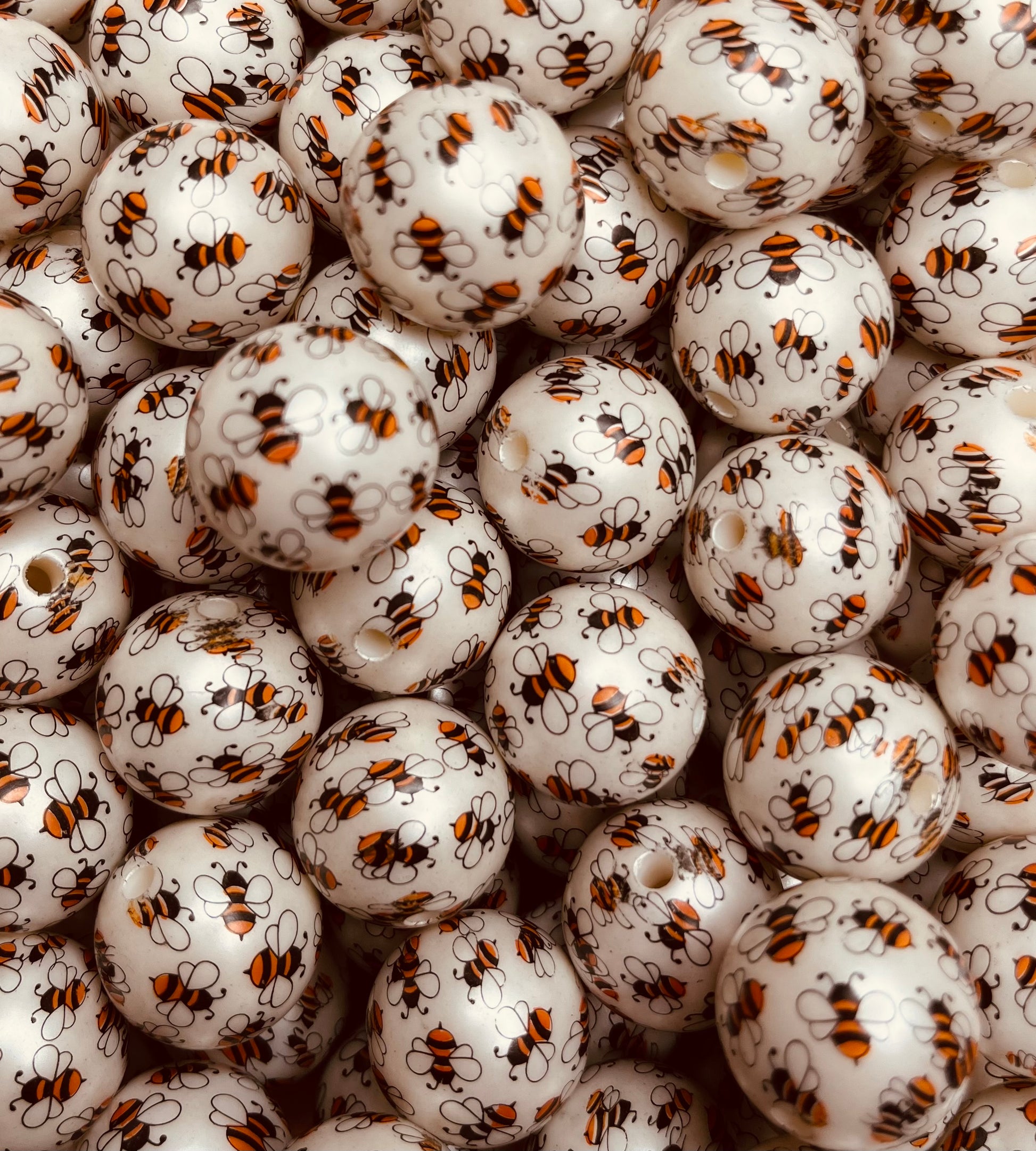 Close-up of white 20mm acrylic bubblegum beads printed with yellow and black bees