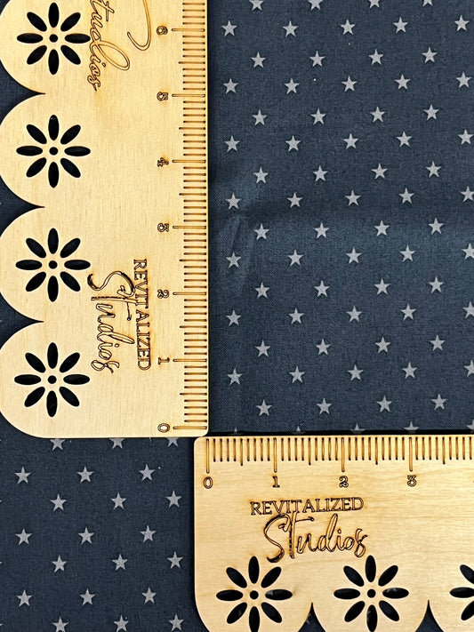 A navy blue fabric with gray stars and a wooden ruler for scale 