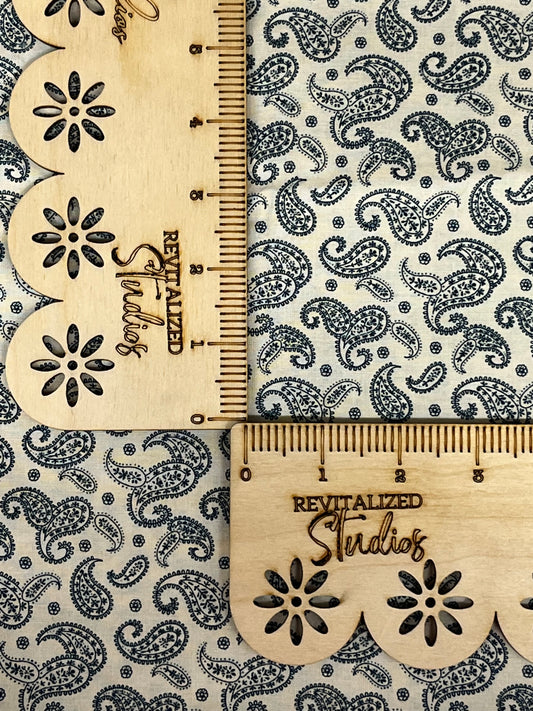 Close-up of Marshall Dry Goods 1800’s reproduction fabric with navy paisley print on light cream background, shown with ruler for scale.