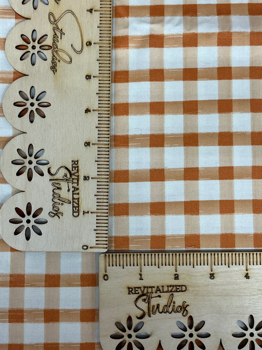 A fabric fat quarter with an orange and white checkered pattern , marked with the brand Riley Blake and designers' names.