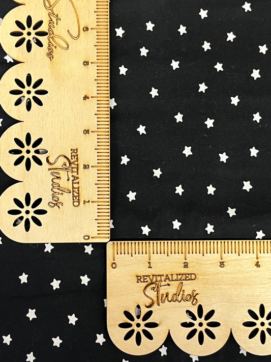 A fabric fat quarter featuring a black background with white stars alongside a wooden ruler for scale