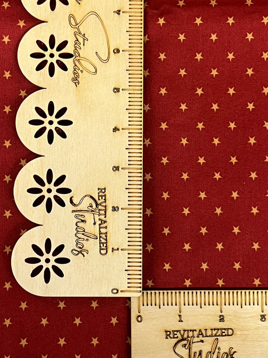 A fat quarter of fabric with red and mustard stars with rulers for scale.
