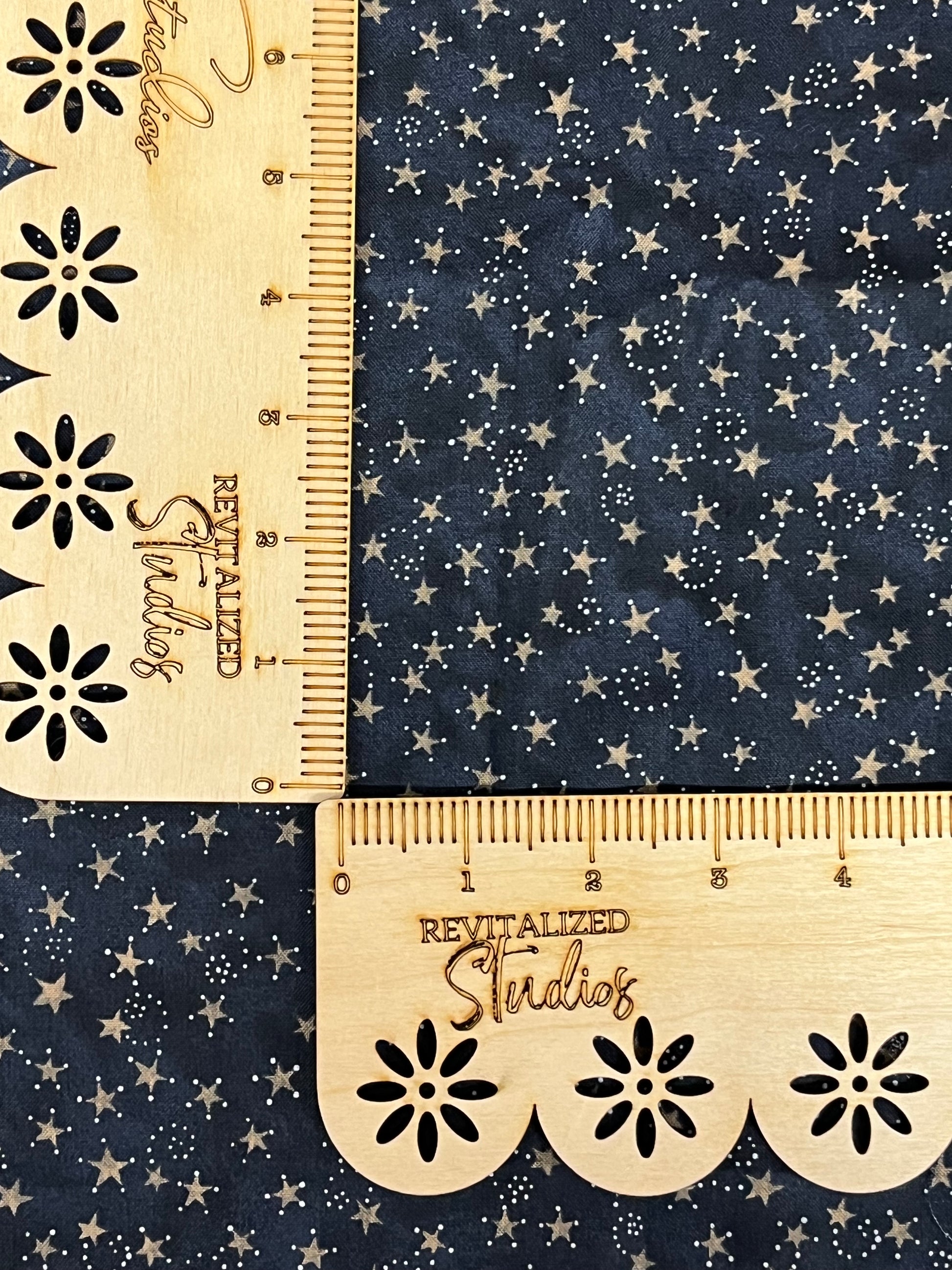 A fat quarter of blue cotton fabric with a pattern of constellations of white stars and dark blue backgrounds, measured with a wooden ruler.