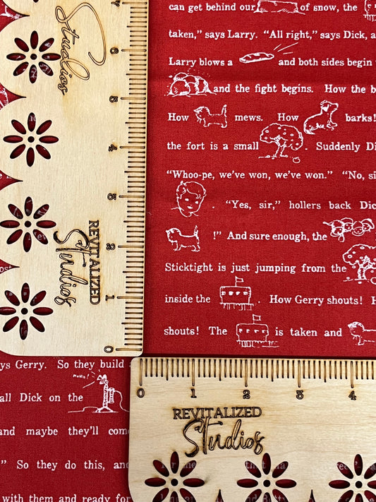 A fabric from Riley Blake Designs featuring a red background with white snowflake patterns and fun sayings in a wooden ruler style font.