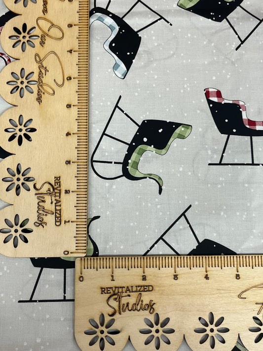 Fabric from the White As Snow Collection by J. Wecker Frisch for Riley Blake Designs, featuring a light gray background with sleighs tossed on top.