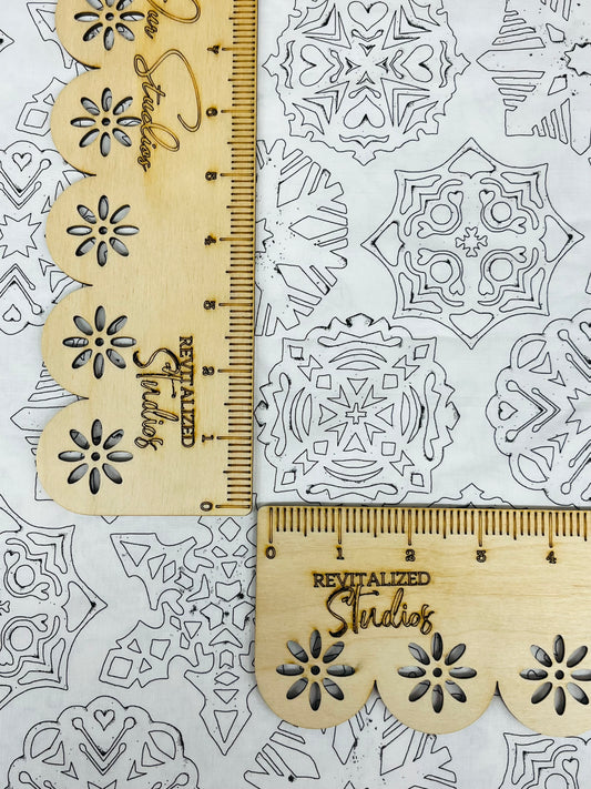 A fat quarter of fabric from the White As Snow collection by J. Wecker Frisch, featuring gray snowflake designs on a white background, measured with a ruler for scale.