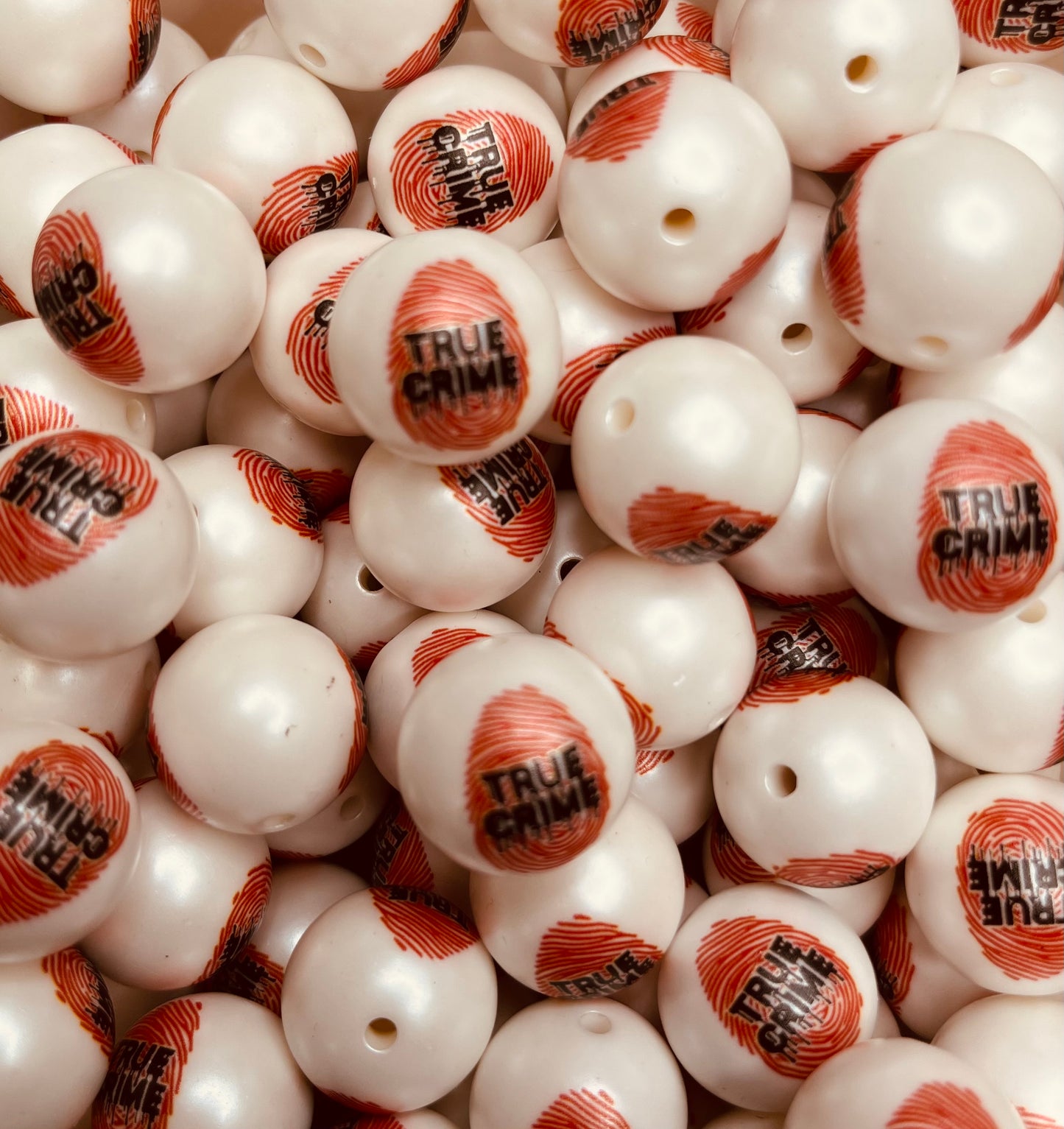 Close-up of 20mm white bubblegum beads with red fingerprint and “True Crime” text design