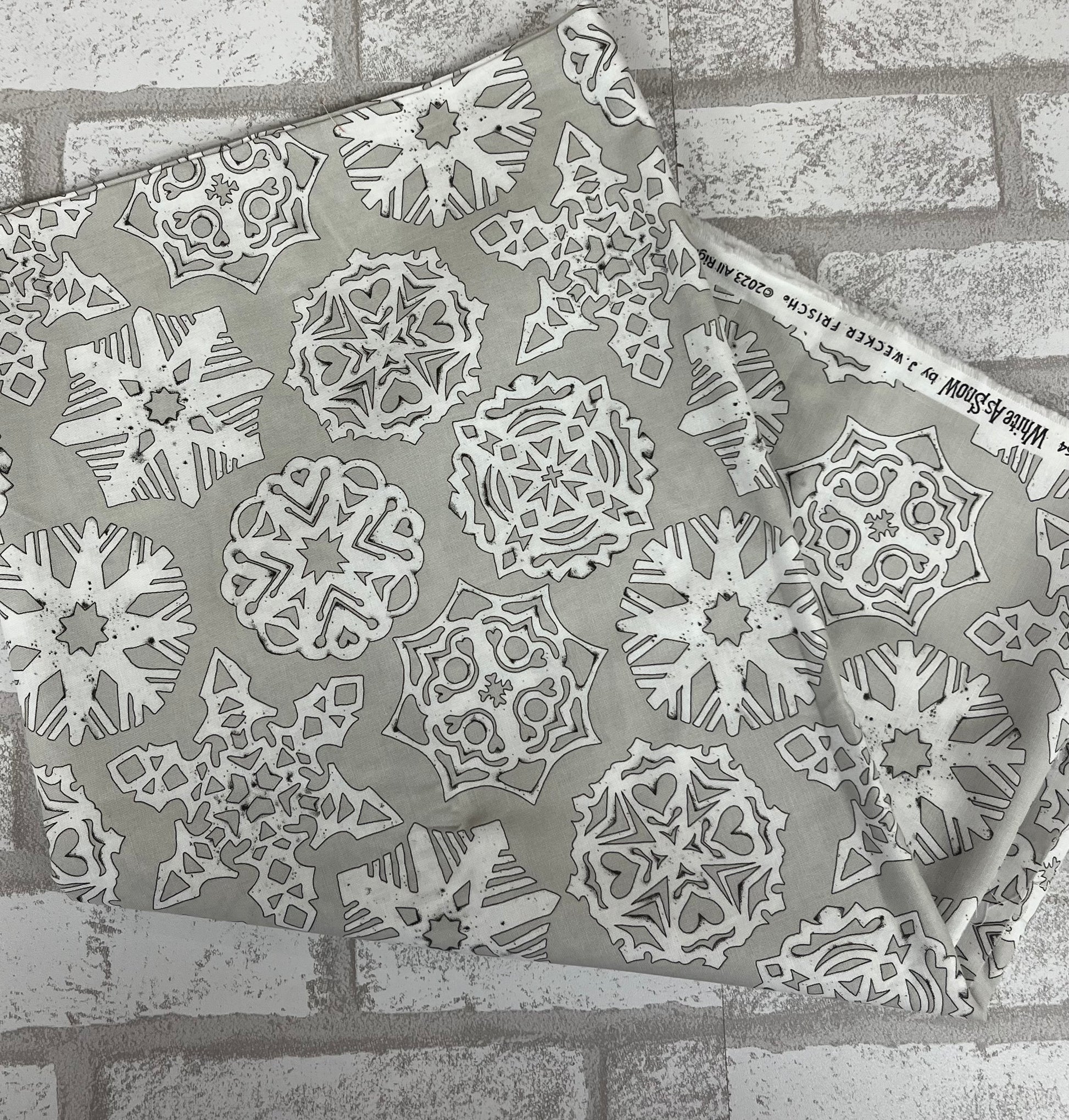 Close-up of Riley Blake White as Snow fat quarter, gray fabric with delicate white snowflakes, perfect for quilting and holiday crafts.