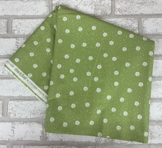 Fabric from the White As Snow Collection with a green background and white snowball patterns, sold in fat quarters.
